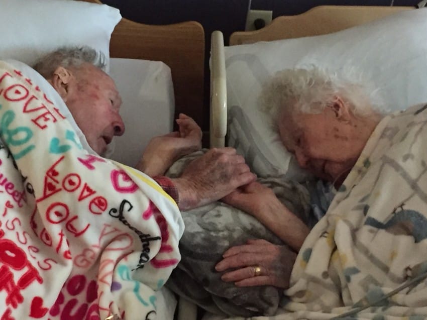 centenarian couple holds hand